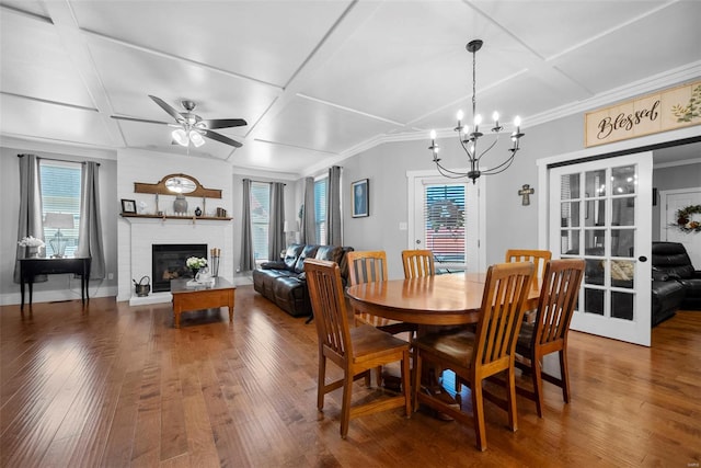 dining area with wood-type flooring, a fireplace, a healthy amount of sunlight, and coffered ceiling