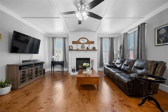 living area with a brick fireplace, ceiling fan, a healthy amount of sunlight, and wood finished floors