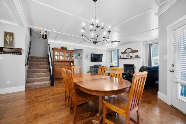 dining area with a brick fireplace, light wood-type flooring, baseboards, coffered ceiling, and stairs