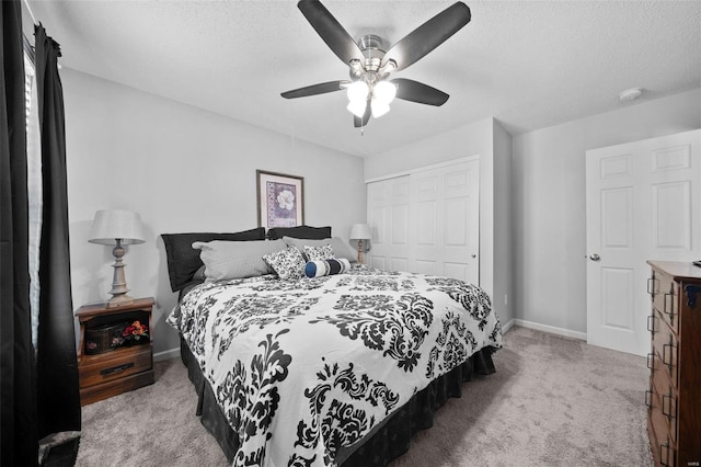 carpeted bedroom with baseboards, ceiling fan, a closet, and a textured ceiling