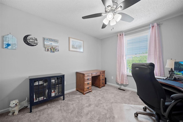 carpeted office with a textured ceiling, ceiling fan, visible vents, and baseboards
