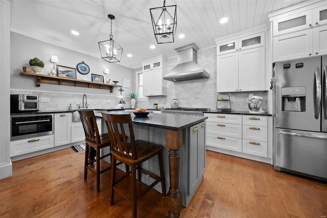 kitchen featuring wall chimney exhaust hood, tasteful backsplash, dark countertops, and stainless steel appliances