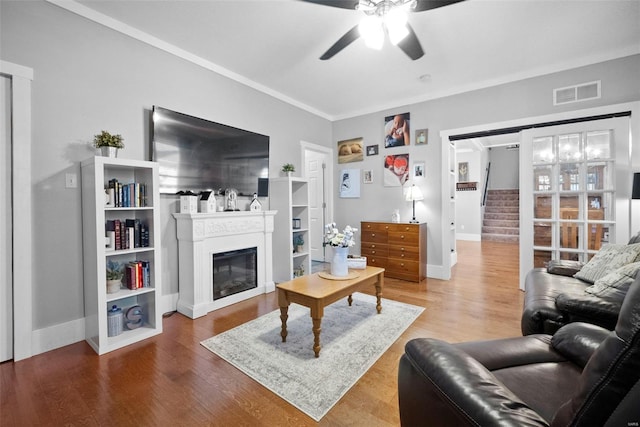 living room with visible vents, a glass covered fireplace, wood finished floors, stairway, and a ceiling fan
