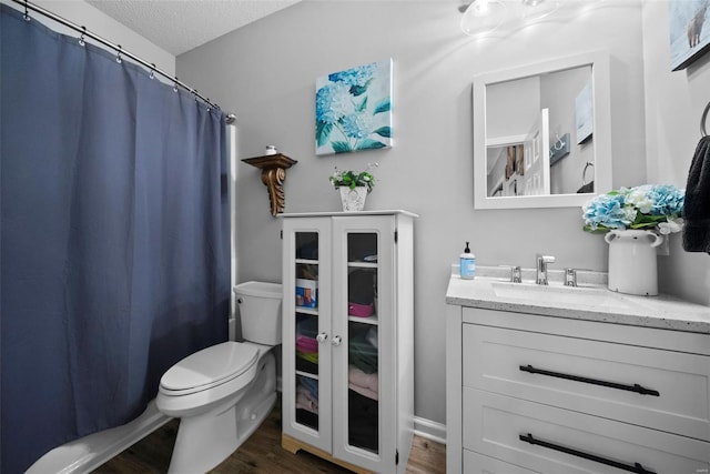 bathroom featuring vanity, toilet, a textured ceiling, a shower with shower curtain, and wood finished floors