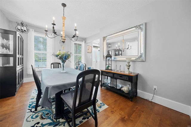 dining space featuring baseboards, wood finished floors, and a notable chandelier