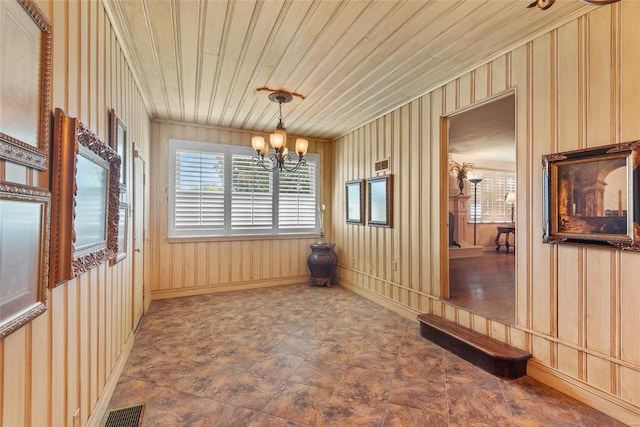 unfurnished dining area featuring an inviting chandelier, stone finish flooring, visible vents, baseboards, and wooden ceiling