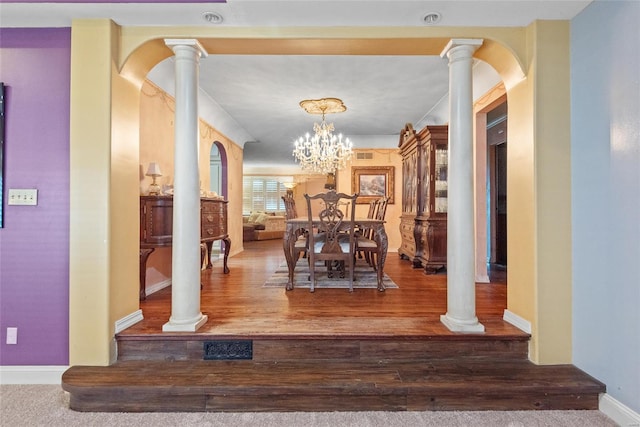 corridor featuring wood finished floors, decorative columns, visible vents, baseboards, and arched walkways