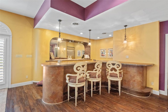 bar with baseboards, wet bar, hanging light fixtures, and dark wood-type flooring