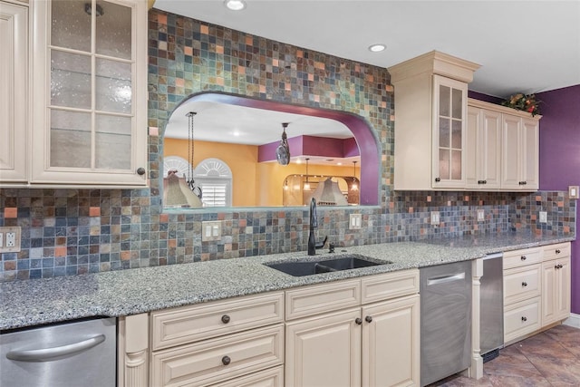 kitchen with glass insert cabinets, a sink, cream cabinetry, stainless steel dishwasher, and tasteful backsplash