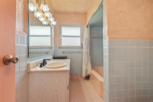 full bath with tile walls, vanity, shower / bath combo, tile patterned floors, and wainscoting