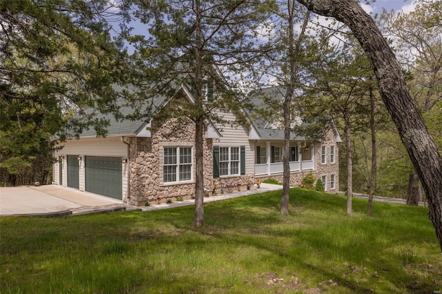view of front facade featuring a garage, concrete driveway, a front lawn, and stone siding
