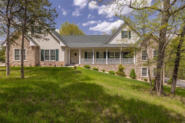 traditional home featuring covered porch, a front yard, and stone siding