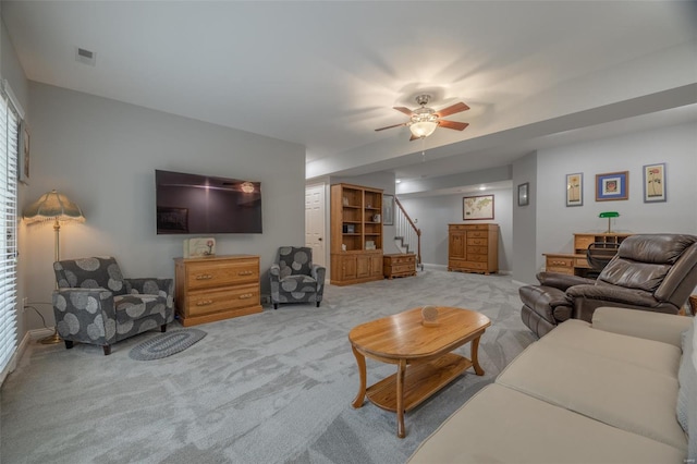 living area with a ceiling fan, visible vents, stairway, and carpet