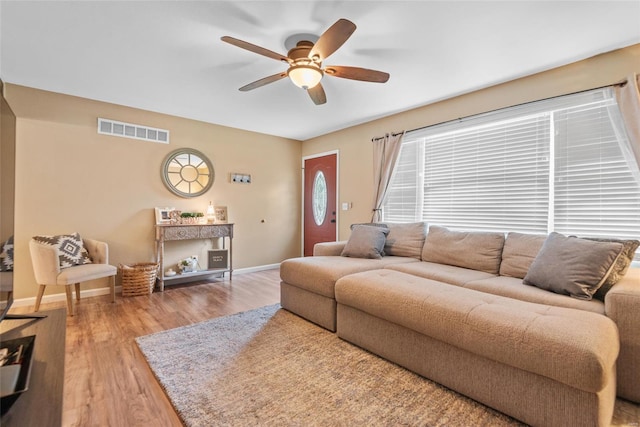 living area with light wood-type flooring, ceiling fan, baseboards, and visible vents
