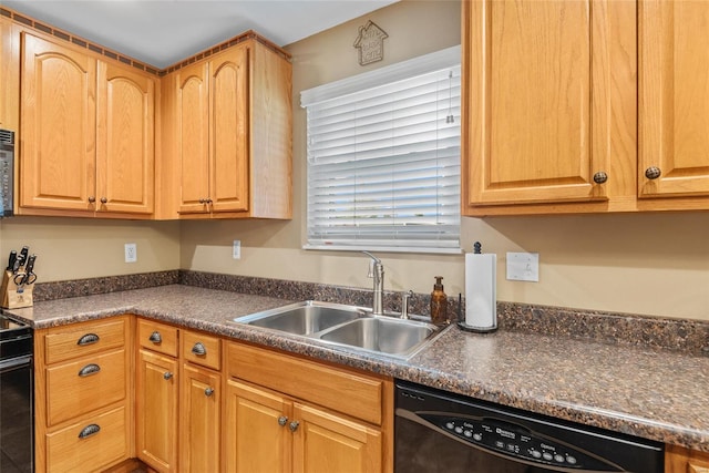 kitchen featuring black appliances, dark countertops, and a sink