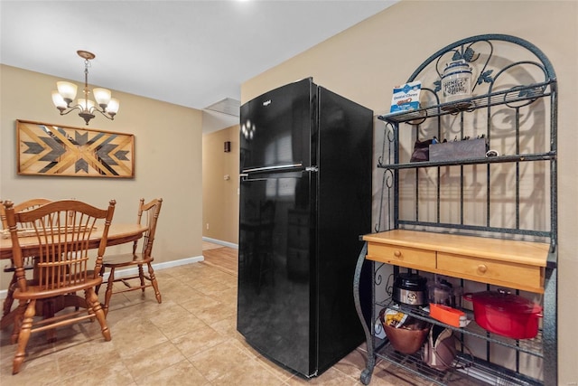 kitchen featuring freestanding refrigerator, an inviting chandelier, tile patterned floors, and baseboards
