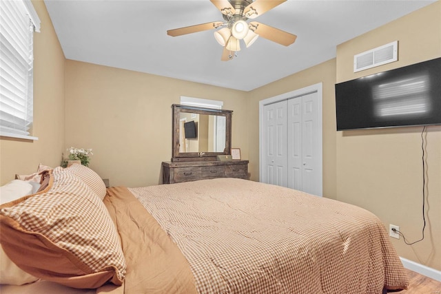 bedroom featuring a ceiling fan, a closet, baseboards, visible vents, and wood finished floors