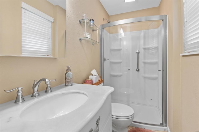 bathroom with a shower stall, vanity, and toilet