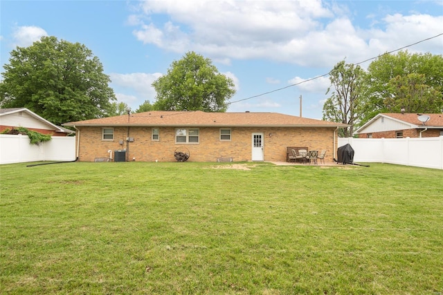 rear view of house with a yard, a fenced backyard, and central AC