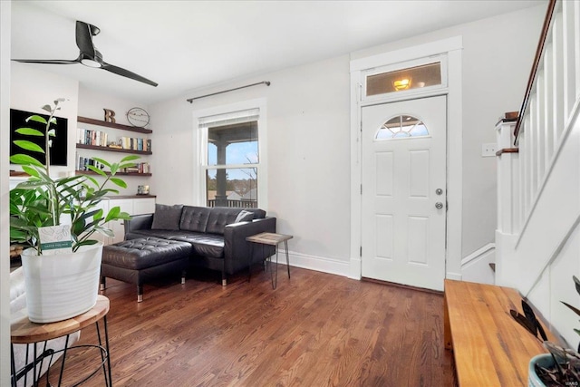 foyer entrance with baseboards, stairs, ceiling fan, and wood finished floors