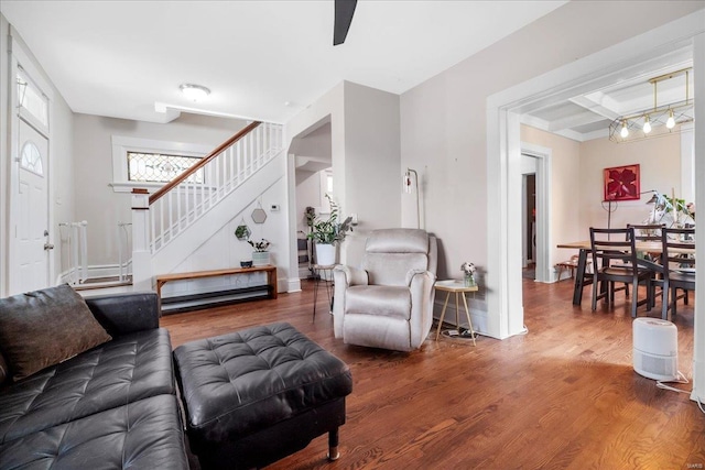 living room featuring stairs, wood finished floors, beamed ceiling, baseboards, and coffered ceiling
