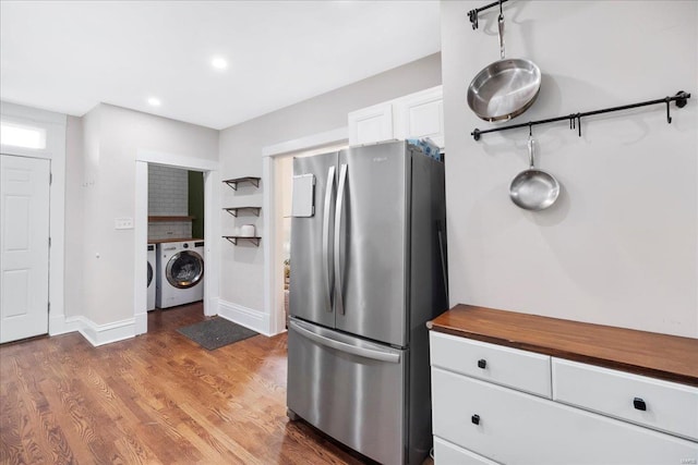 kitchen with butcher block countertops, freestanding refrigerator, white cabinetry, wood finished floors, and washer and clothes dryer