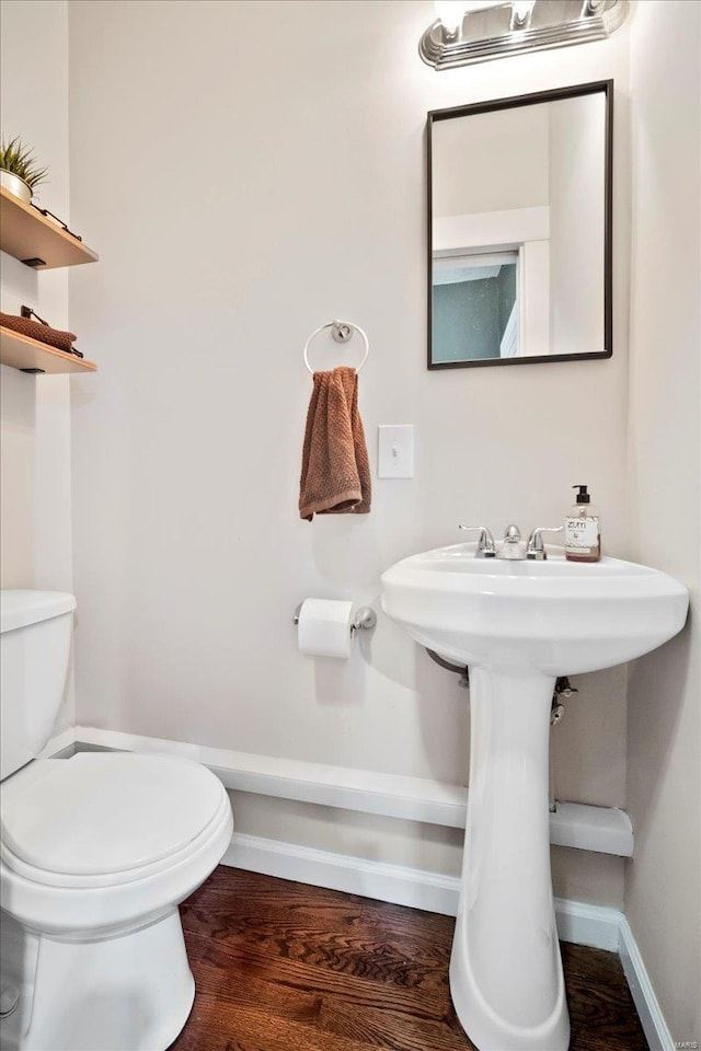 bathroom with toilet, baseboards, and wood finished floors
