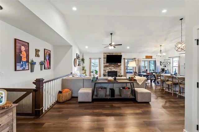living area with dark wood-style flooring, a stone fireplace, and a wealth of natural light