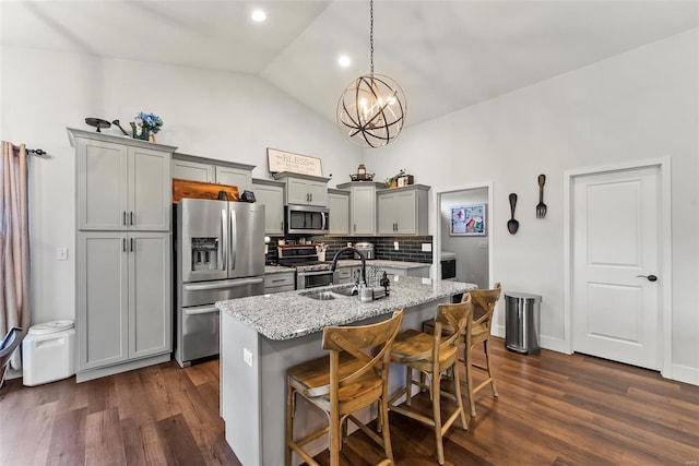 kitchen with backsplash, dark wood-style flooring, gray cabinetry, a sink, and stainless steel appliances