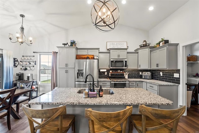 kitchen with backsplash, stainless steel appliances, a notable chandelier, and gray cabinetry