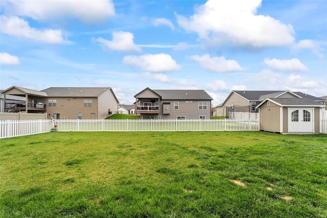 view of yard with a residential view, an outdoor structure, a fenced backyard, and a storage unit