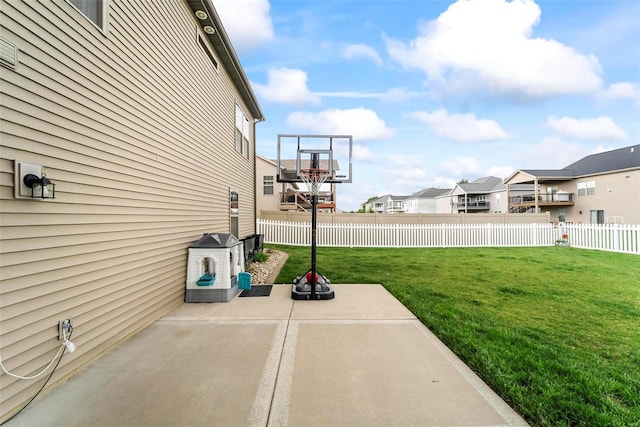 view of basketball court featuring a lawn, fence, and a residential view