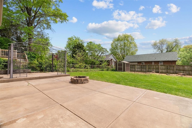 view of patio with an outbuilding, a shed, a fenced backyard, and an outdoor fire pit