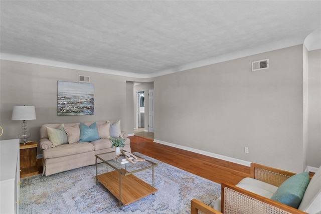 living room featuring visible vents, baseboards, and wood finished floors