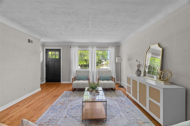 living room featuring visible vents, a textured ceiling, baseboards, and wood finished floors