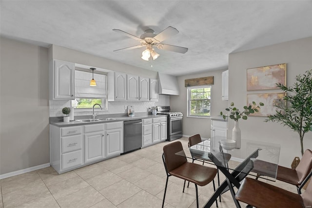 kitchen featuring a ceiling fan, appliances with stainless steel finishes, tasteful backsplash, a sink, and custom range hood