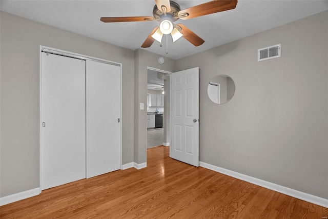 unfurnished bedroom featuring a closet, baseboards, visible vents, and light wood-style floors