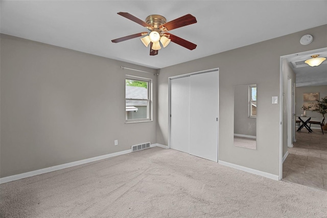 unfurnished bedroom featuring ceiling fan, visible vents, baseboards, carpet floors, and a closet
