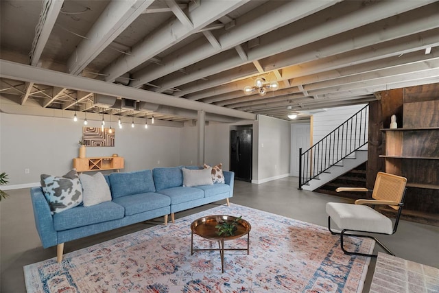 living room with baseboards, concrete flooring, and stairway