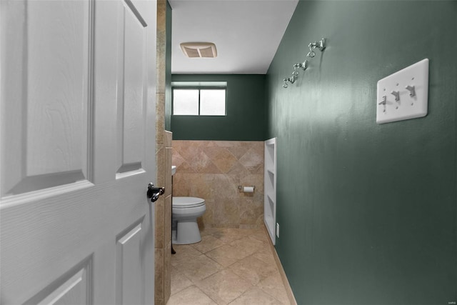 bathroom featuring visible vents, tile patterned floors, toilet, and tile walls