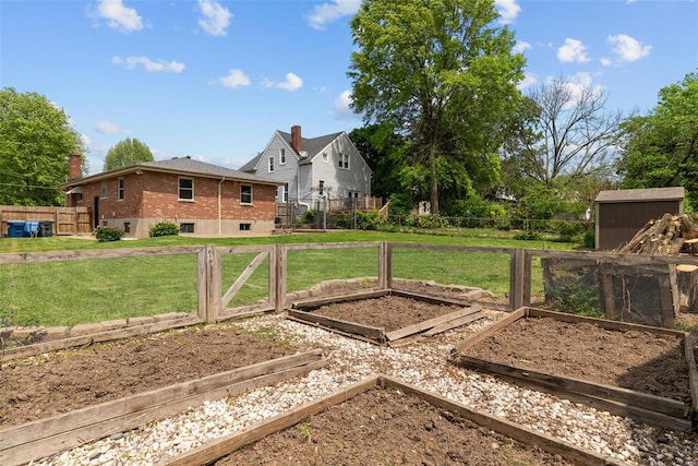 view of yard with fence, an outbuilding, a shed, and a vegetable garden