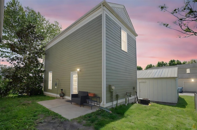 view of home's exterior with a patio, an outdoor structure, a lawn, and central AC