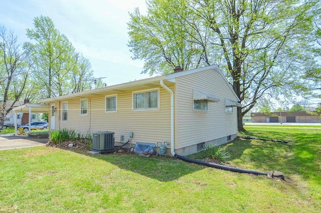 view of property exterior with an attached carport, a chimney, a yard, and cooling unit