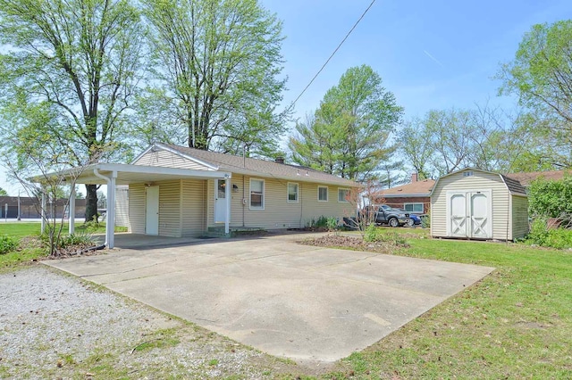 view of front of home with driveway, a carport, an outdoor structure, a front lawn, and a storage unit