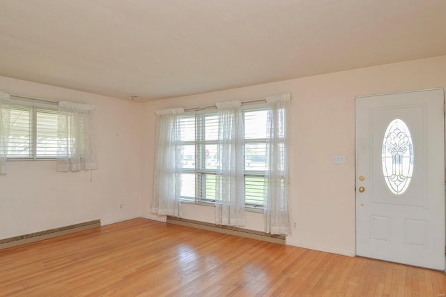 entrance foyer featuring light wood-style floors, baseboard heating, and a wealth of natural light