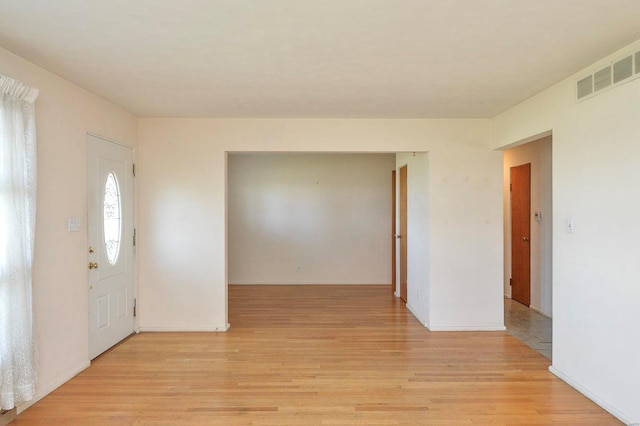 foyer entrance featuring baseboards, visible vents, and light wood finished floors
