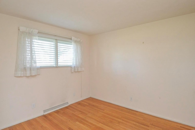 spare room with baseboards, light wood-style flooring, and visible vents