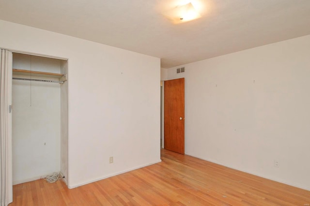 unfurnished bedroom with light wood-style floors, a closet, and visible vents