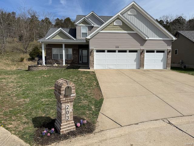 craftsman inspired home featuring an attached garage, concrete driveway, brick siding, and a front yard