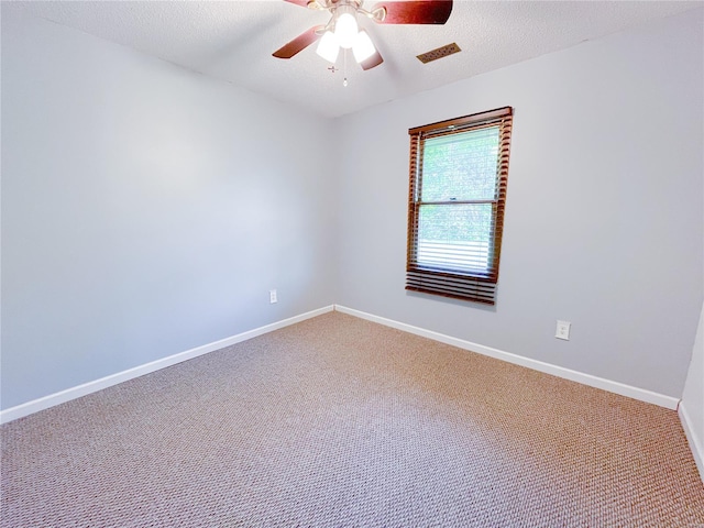 carpeted spare room featuring baseboards, a ceiling fan, a textured ceiling, and visible vents